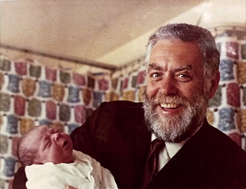 Denys Fisher smiling as he holds his baby son, Duncan.