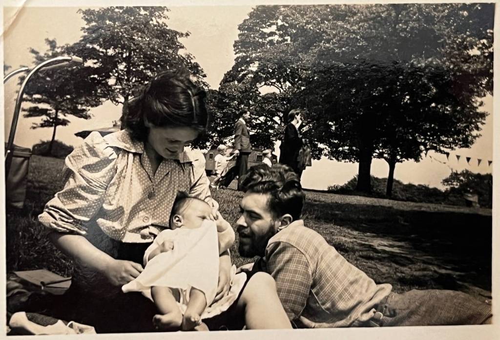 Denys Fisher and his wife Betty gazing adoringly at their first baby, Cherry, as they lounge in Roundhay Park, Leeds.